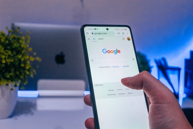 Photo of a hand holding a phone searching for something on Google by Arkan Perdana on Unsplash