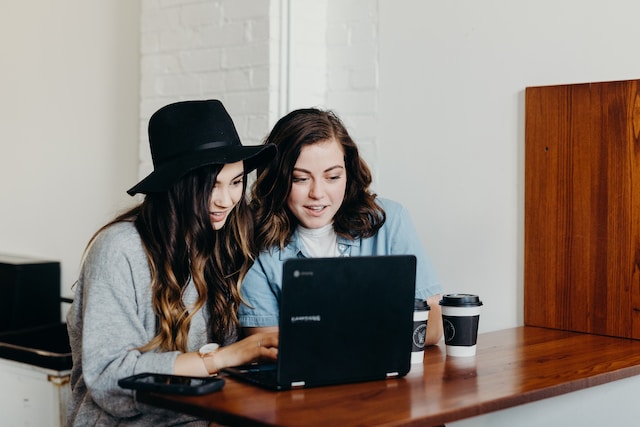 Photo of two bloggers crowded around a laptop by Brooke Cagle on Unsplash