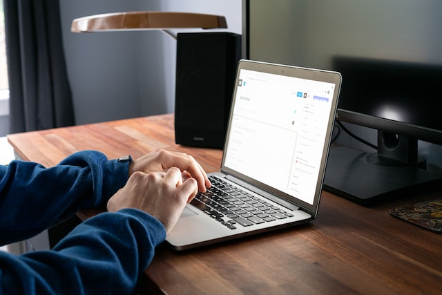 Photo of a person writing a blog post with a laptop on a wooden table by Justin Morgan on Unsplash